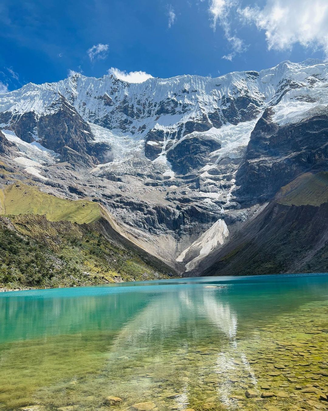 Vista panorámica de la Laguna Humantay, con sus aguas azul turquesa que contrastan con las montañas nevadas a su alrededor.