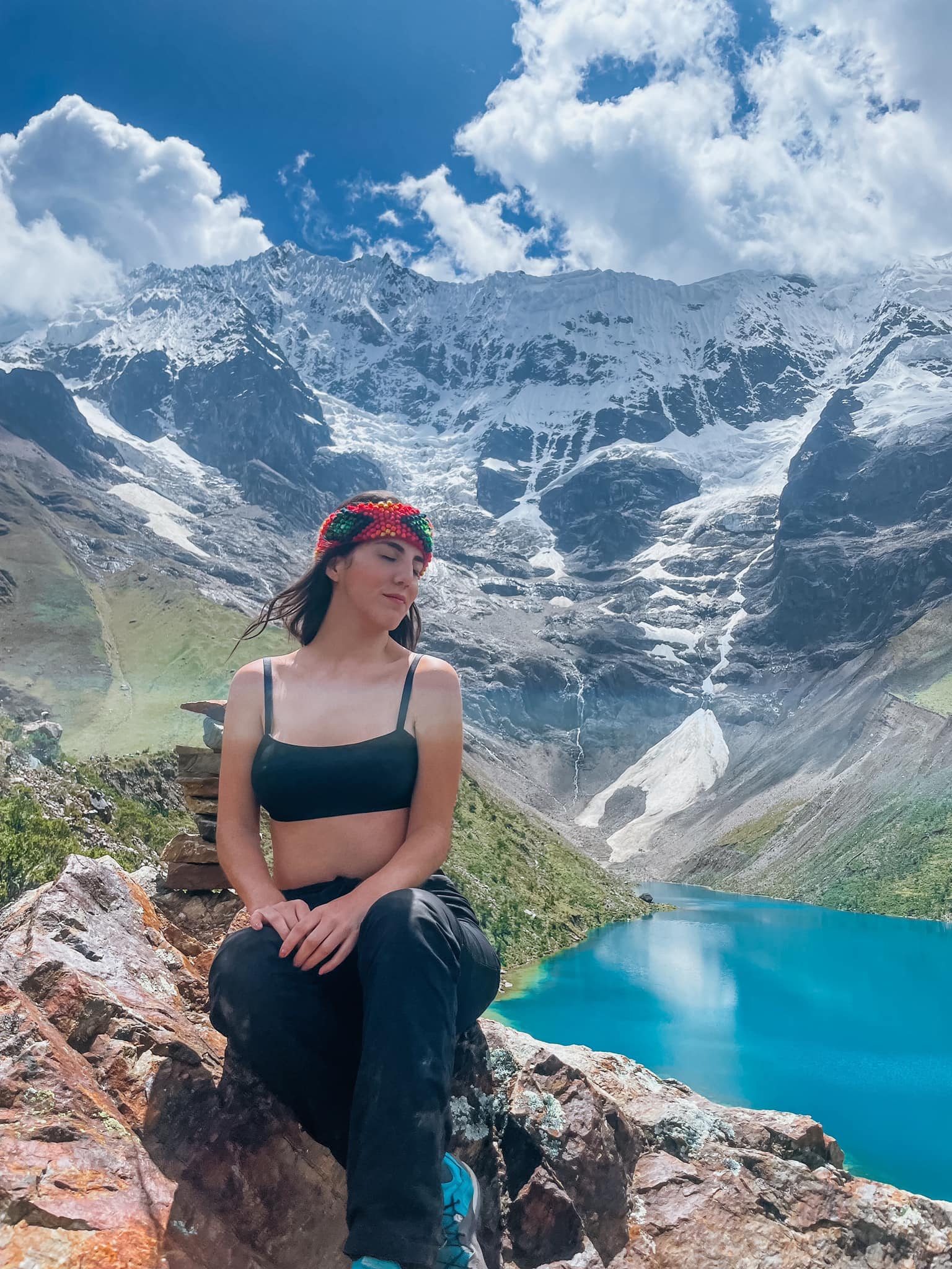 Reflejo azul-turquesa de la Laguna Humantay bajo el cielo andino, rodeada de picos nevados y terreno rocoso.